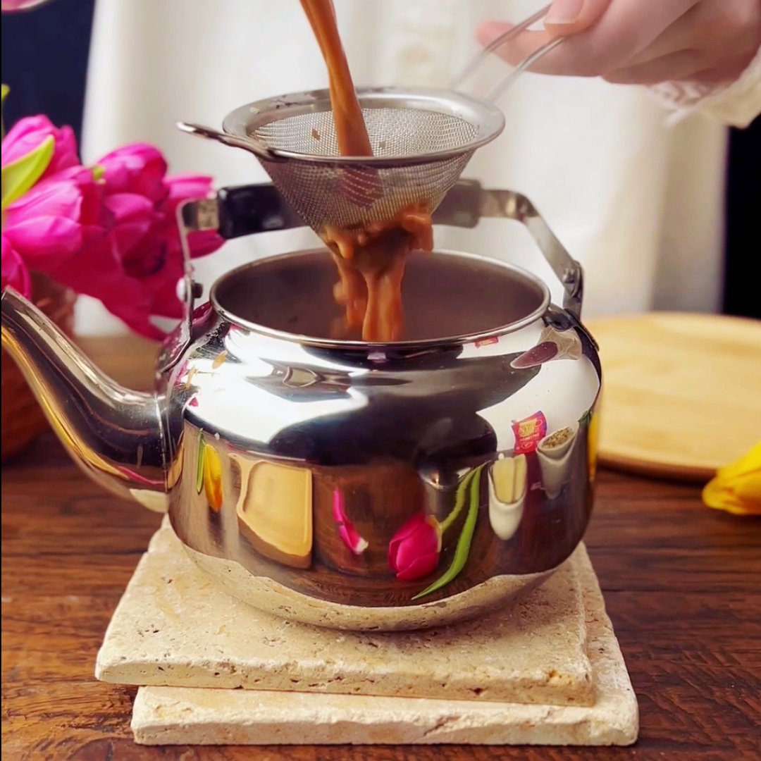 pouring traditional chai tea in a cup